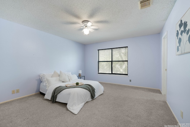 carpeted bedroom featuring ceiling fan and a textured ceiling