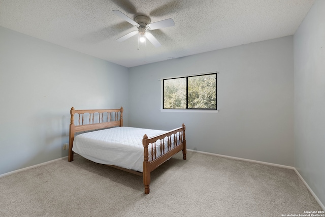 carpeted bedroom featuring ceiling fan and a textured ceiling