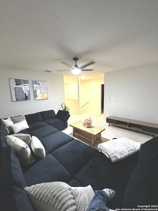 living room featuring a textured ceiling, carpet flooring, and ceiling fan