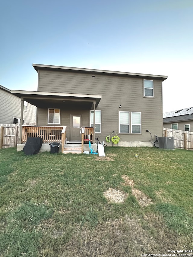 back of property featuring central AC unit and a lawn