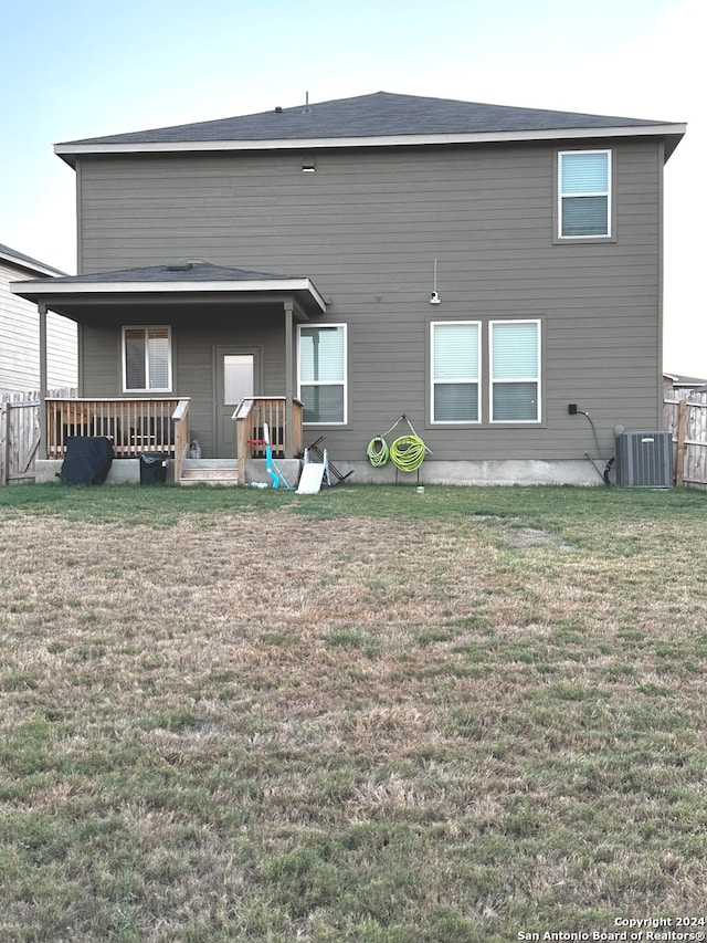 back of house with central air condition unit and a yard