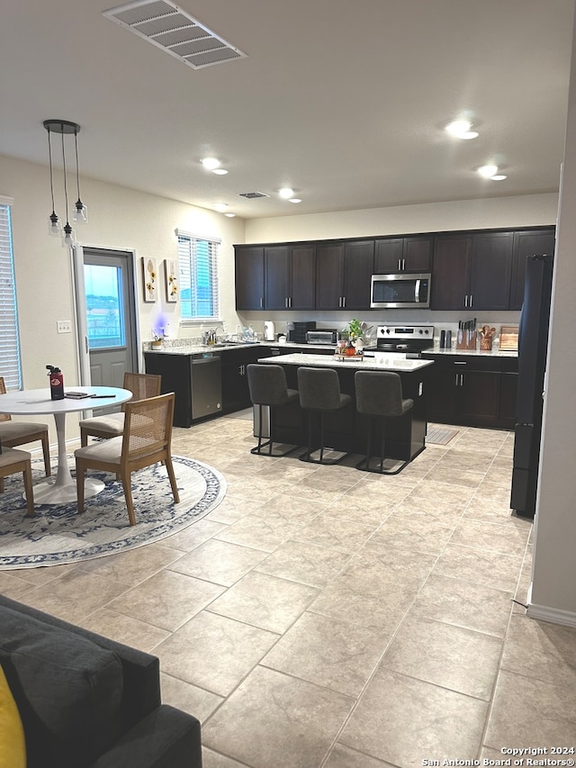 kitchen featuring stainless steel appliances, a kitchen bar, pendant lighting, and a center island