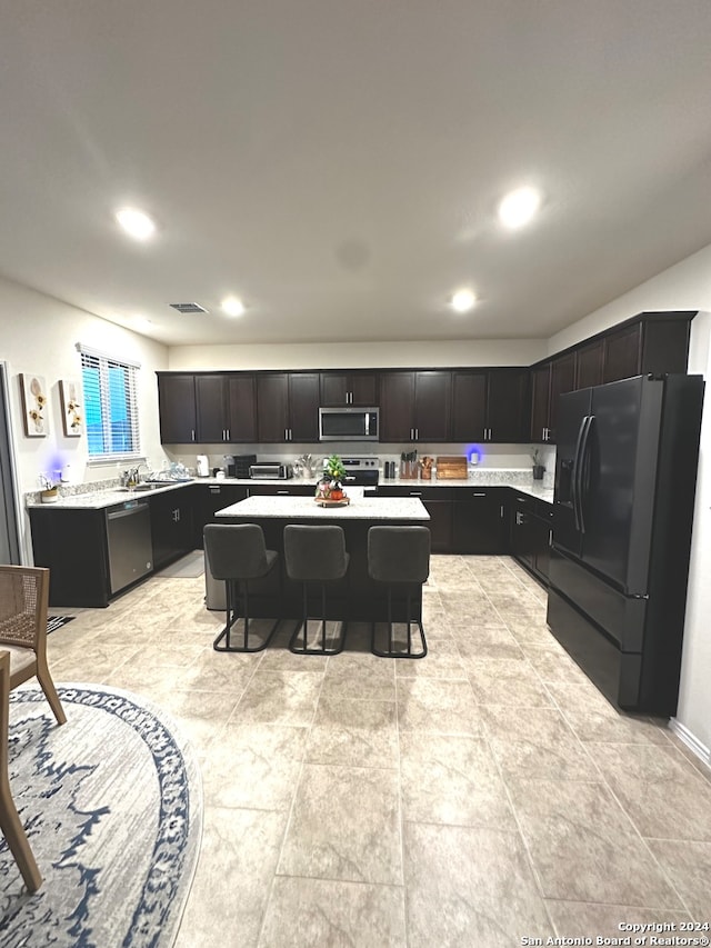 kitchen with a kitchen breakfast bar, black appliances, and a kitchen island