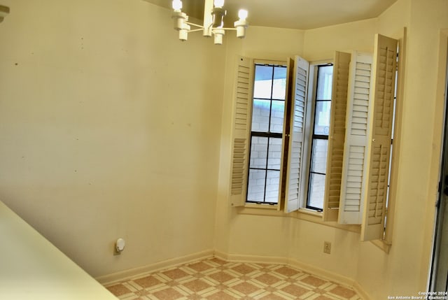 unfurnished room with a notable chandelier