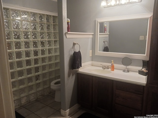 bathroom featuring tile patterned flooring, walk in shower, vanity, and toilet