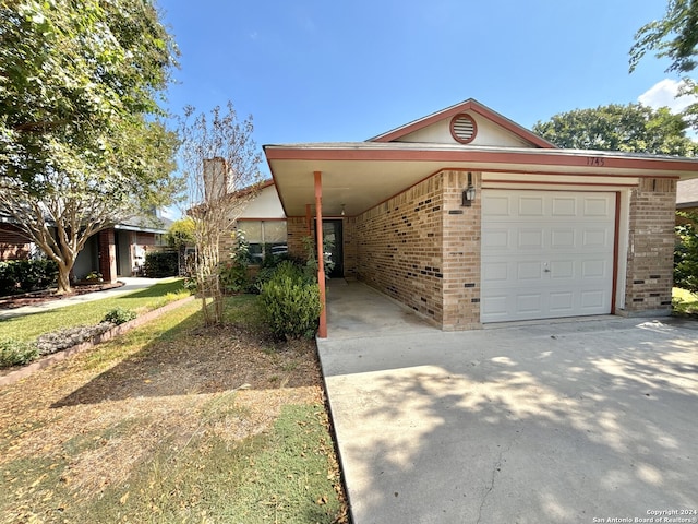 view of front of home with brick siding, an attached carport, driveway, and a garage