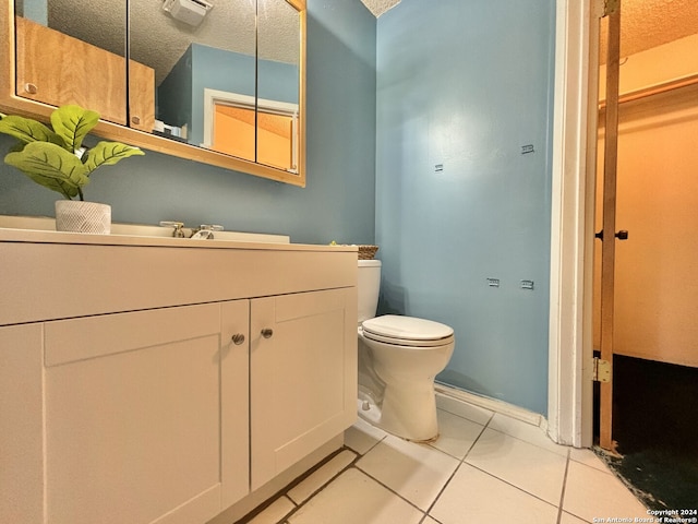 bathroom with tile patterned floors, toilet, vanity, a textured ceiling, and baseboards