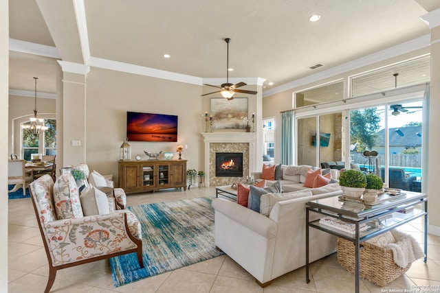 living room with ornamental molding, decorative columns, light tile patterned floors, and ceiling fan with notable chandelier