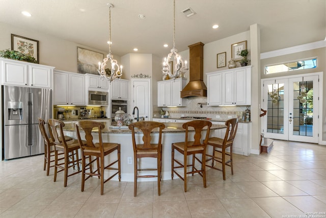 kitchen featuring french doors, white cabinets, appliances with stainless steel finishes, and a kitchen island with sink