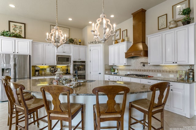 kitchen featuring a center island with sink, dark stone counters, a chandelier, and stainless steel appliances