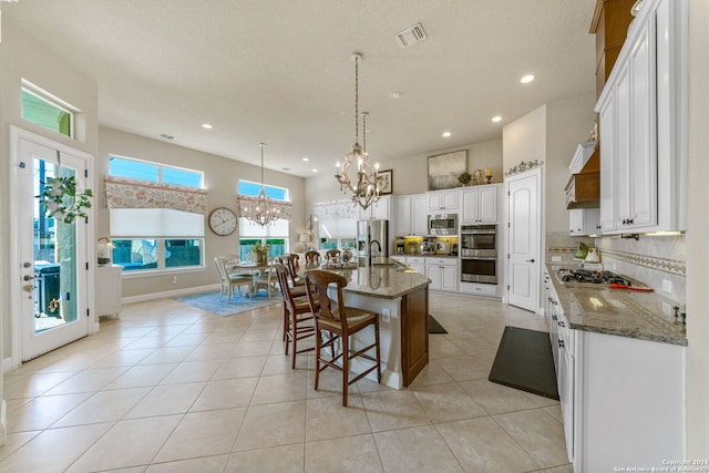 kitchen featuring a kitchen island with sink, white cabinets, sink, appliances with stainless steel finishes, and a kitchen breakfast bar