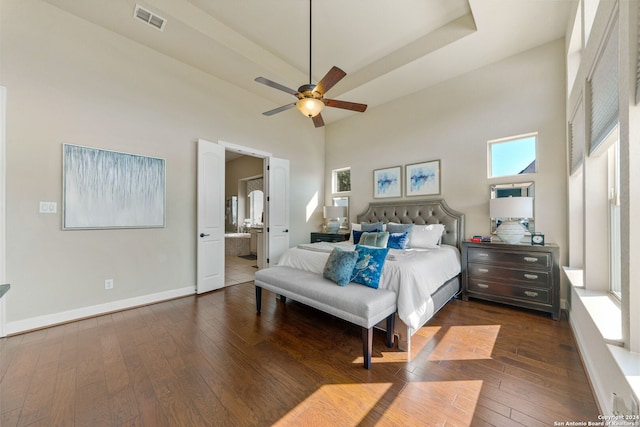 bedroom with a towering ceiling, dark wood-type flooring, ensuite bathroom, and ceiling fan