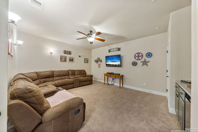 living room with light carpet, ceiling fan, and a textured ceiling