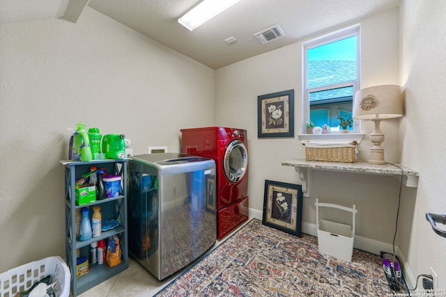 clothes washing area with washer and dryer, tile patterned floors, and a textured ceiling