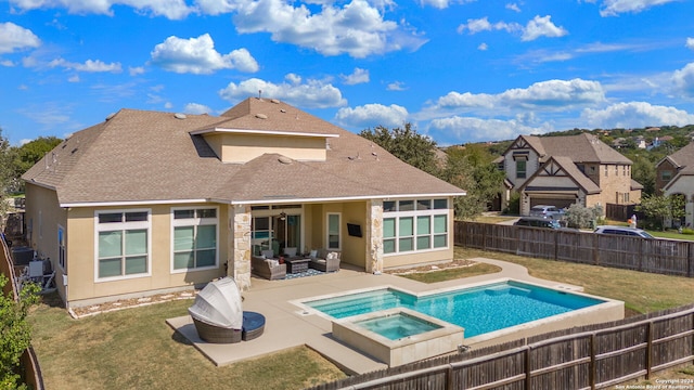 rear view of house featuring an in ground hot tub, a patio, and a lawn