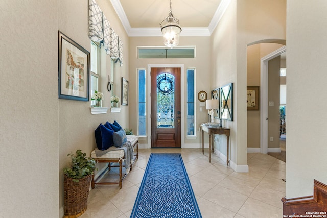 tiled foyer entrance with ornamental molding, a high ceiling, and a chandelier