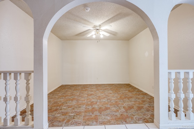 empty room with ceiling fan and a textured ceiling