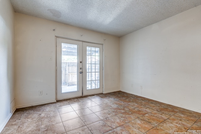 empty room featuring a textured ceiling and french doors