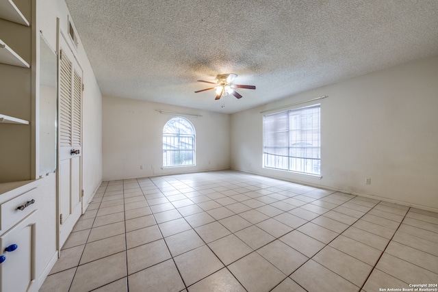 tiled empty room with ceiling fan and a textured ceiling