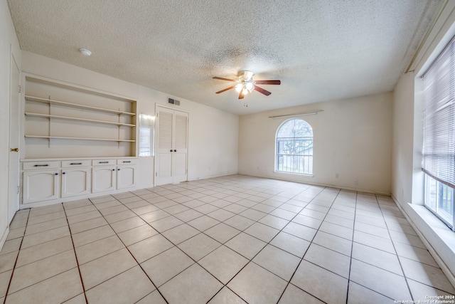 unfurnished living room featuring ceiling fan, a textured ceiling, and light tile patterned flooring