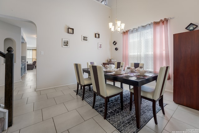 dining space with a high ceiling, light tile patterned flooring, a notable chandelier, and a wealth of natural light