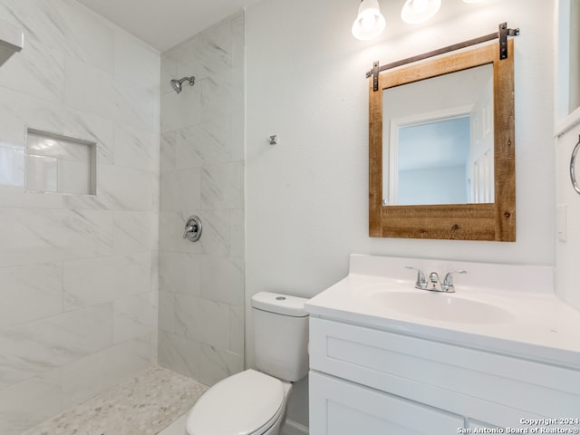 bathroom featuring tiled shower, toilet, and vanity