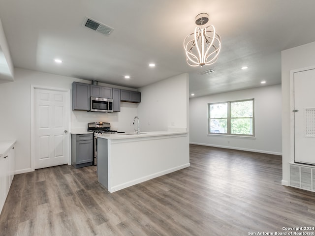 kitchen with gray cabinetry, stainless steel appliances, decorative light fixtures, dark hardwood / wood-style floors, and sink