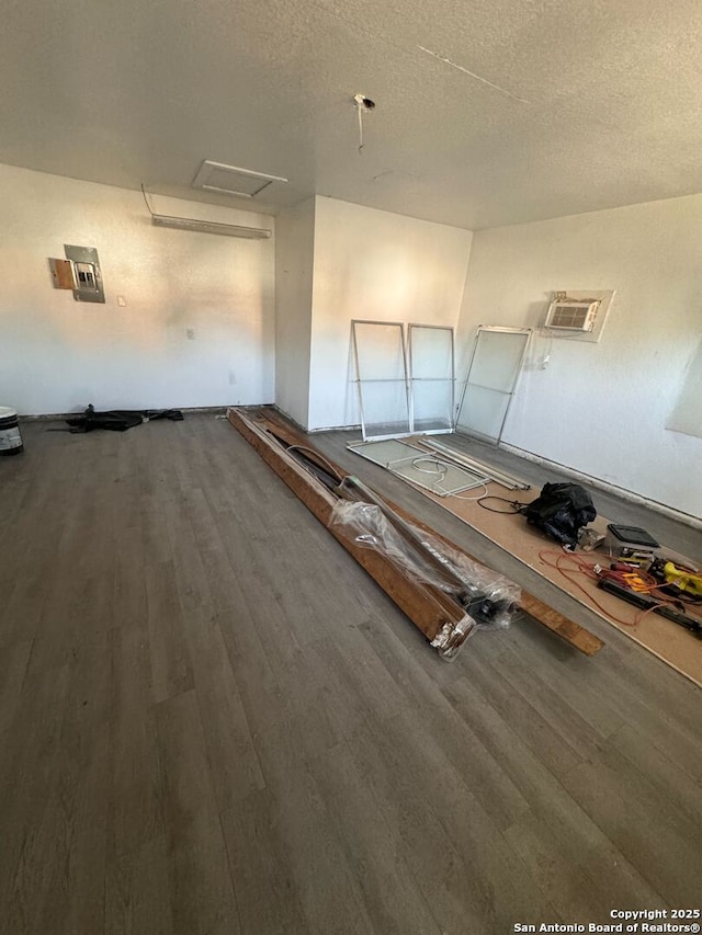 interior space featuring hardwood / wood-style flooring, a wall mounted AC, and a textured ceiling