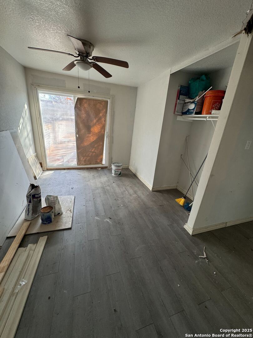 unfurnished living room with ceiling fan, dark hardwood / wood-style floors, and a textured ceiling