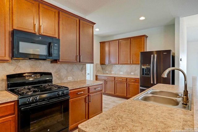 kitchen featuring tasteful backsplash, brown cabinets, light countertops, black appliances, and a sink