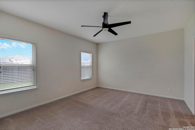 carpeted empty room featuring baseboards and a ceiling fan