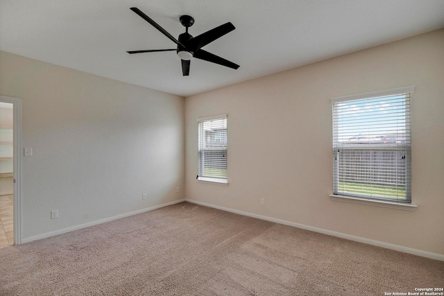 empty room featuring light carpet, baseboards, and a ceiling fan