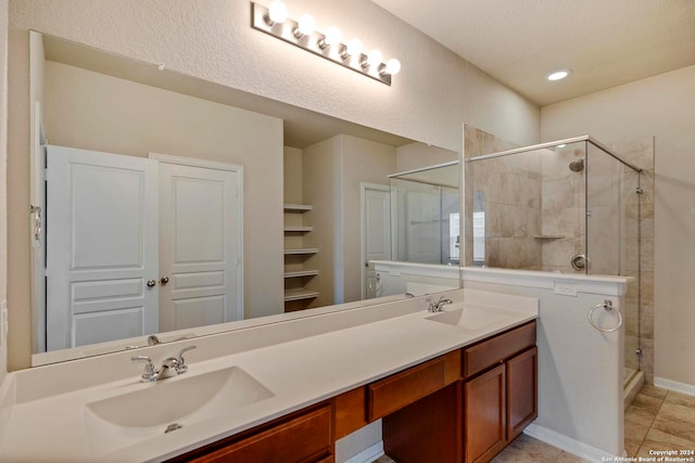 bathroom featuring a stall shower, a sink, baseboards, and double vanity