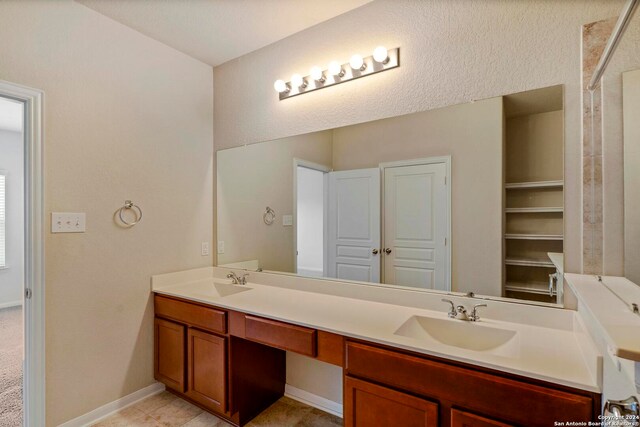 full bath with double vanity, baseboards, and a sink