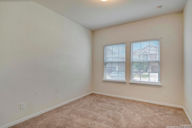 unfurnished room with light colored carpet and baseboards