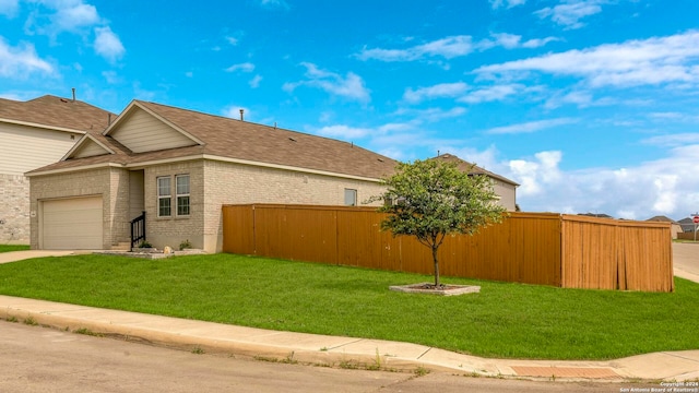 view of side of property featuring a garage, brick siding, fence, a yard, and concrete driveway