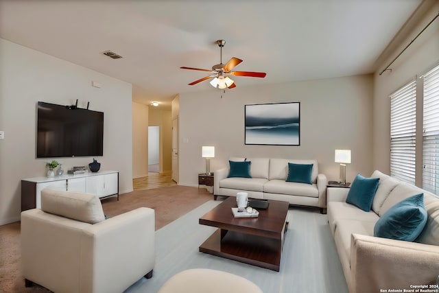 living area featuring a ceiling fan, light colored carpet, and visible vents