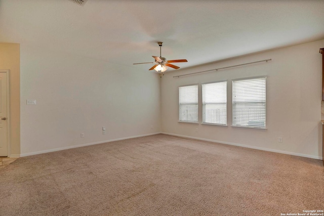 empty room with baseboards, ceiling fan, and light colored carpet