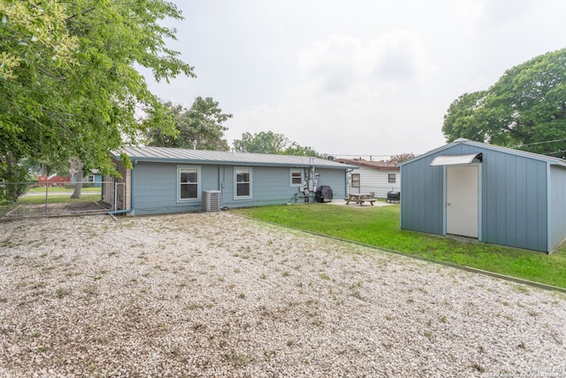 rear view of property with a storage shed, central air condition unit, and a yard