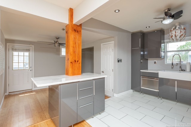 kitchen featuring gray cabinets, light hardwood / wood-style floors, ceiling fan, and sink