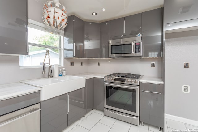 kitchen with gray cabinets, light tile patterned flooring, sink, and stainless steel appliances