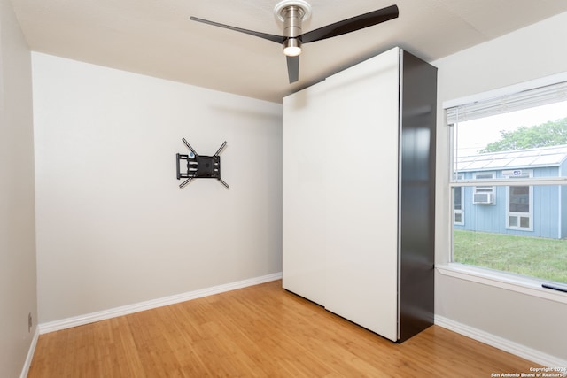 unfurnished room with cooling unit, light hardwood / wood-style floors, and ceiling fan