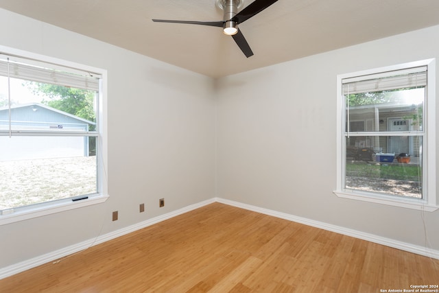 spare room featuring wood-type flooring, ceiling fan, and a wealth of natural light