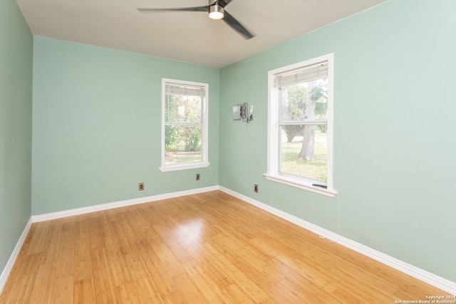 spare room with light wood-type flooring, ceiling fan, and plenty of natural light