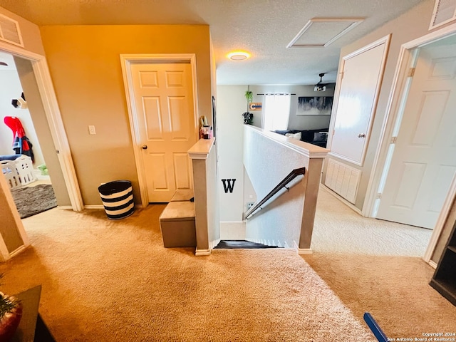 hall featuring a textured ceiling and light colored carpet