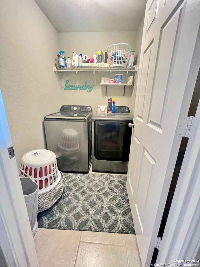 clothes washing area featuring a textured ceiling, washing machine and dryer, and light tile patterned floors