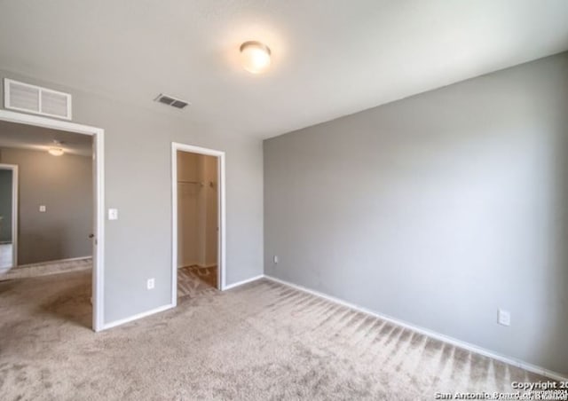 unfurnished bedroom featuring light colored carpet, a closet, and a walk in closet