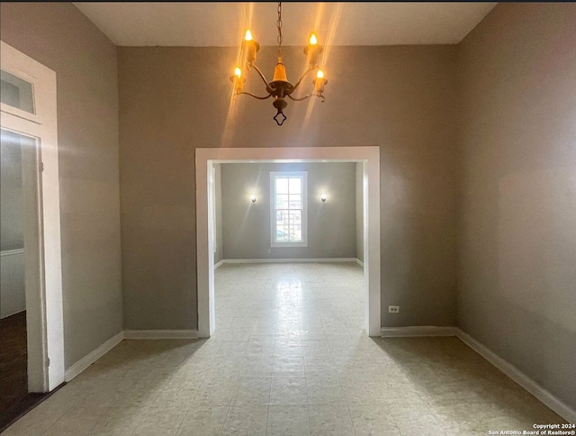 unfurnished room featuring a chandelier