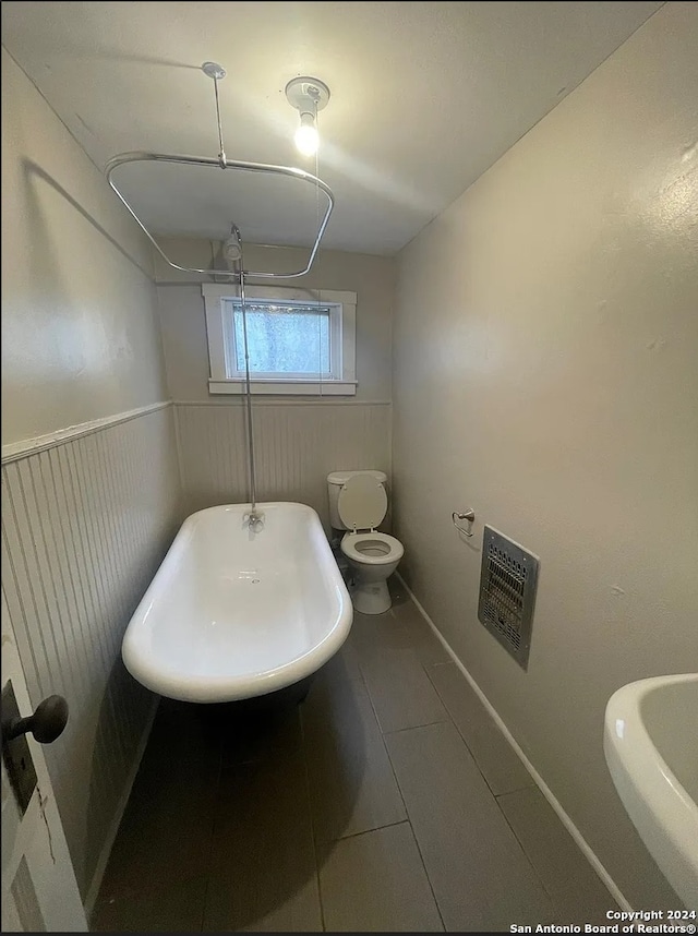 bathroom with tile patterned flooring, toilet, and heating unit