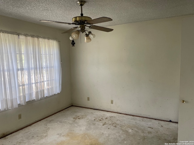 empty room with ceiling fan and a textured ceiling